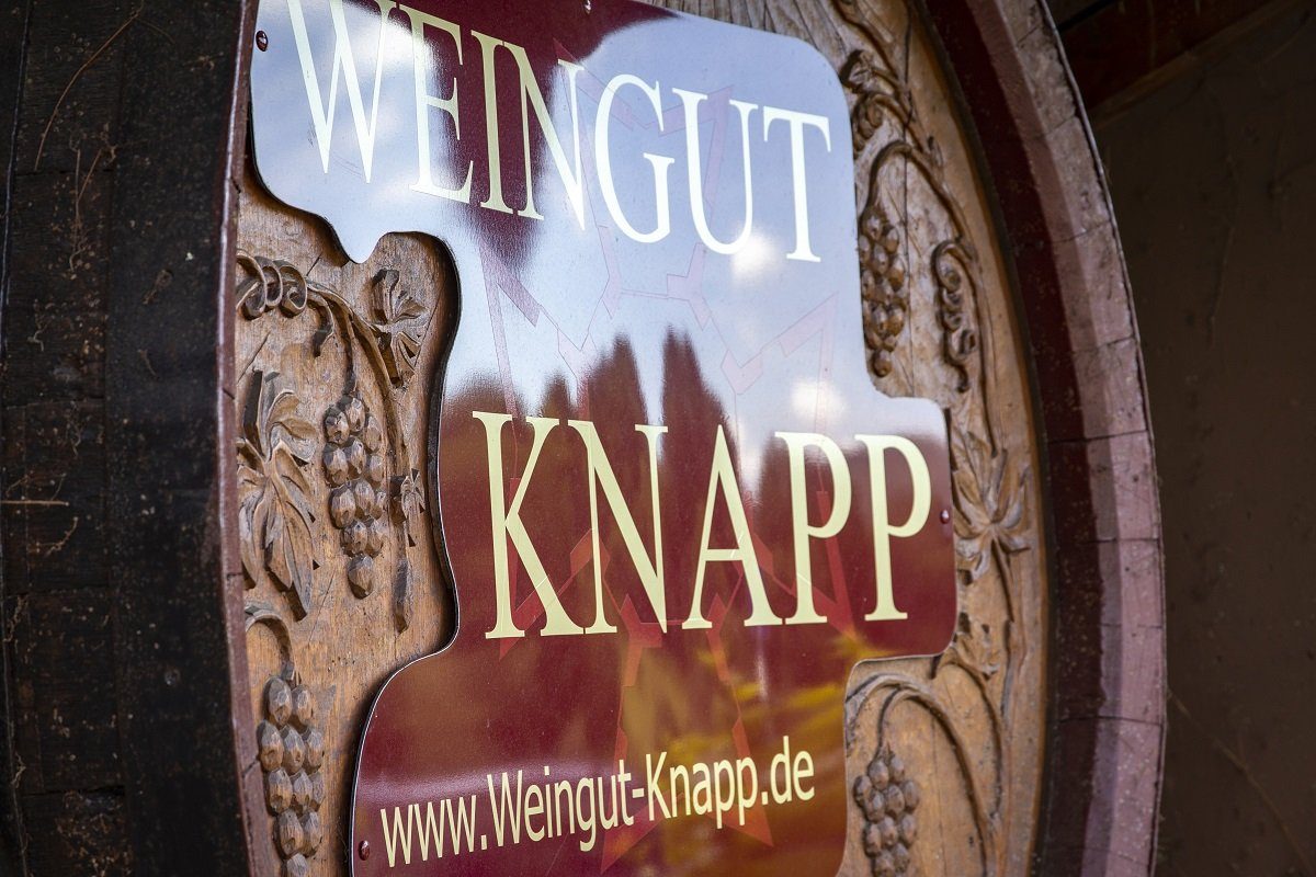 Geschnitzter Fassboden mit dem Wappen und Schriftzug ‚Weingut Knapp‘ im Keller